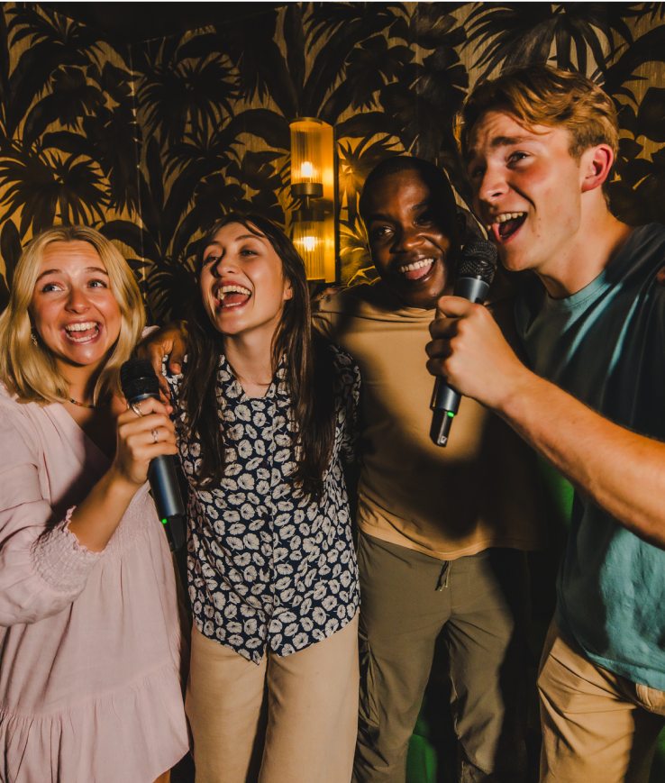 A lively group of people in a karaoke room, joyfully smiling in celebration and excitement.